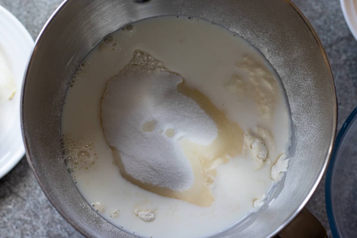 milk, sugar, yeast, salt, and flour are placed in a bowl of a stand mixer