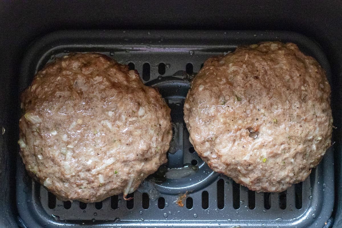2 burger patties are cooked in an air fryer