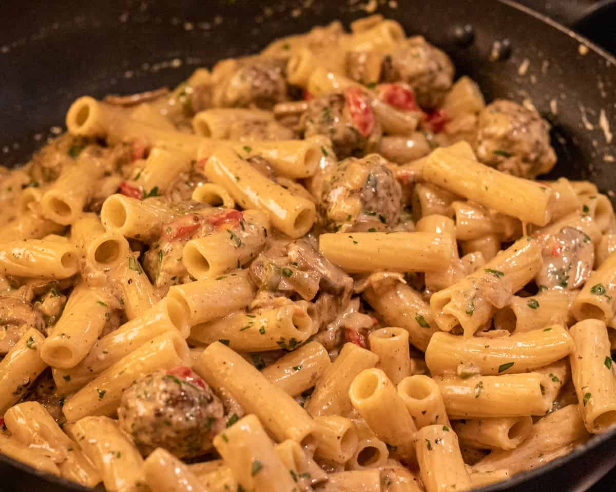 creamy sauce is mixed with cooked pasta