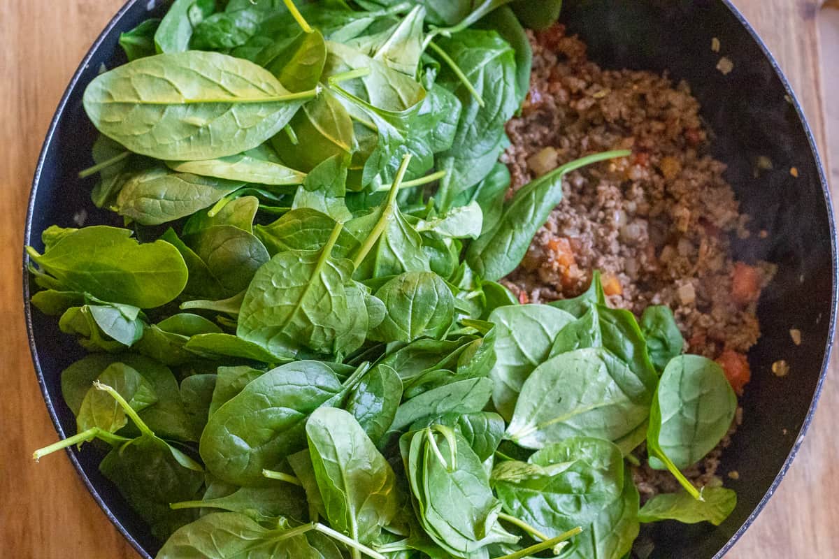 baby spinach leaves are added to the pan