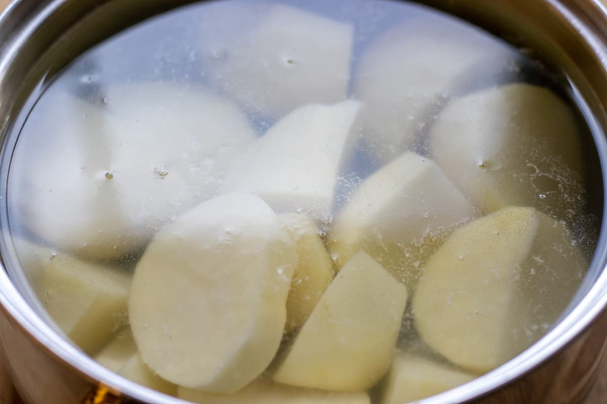 the potatoes are peeled, cut  in chunks and placed in a pan with cold water