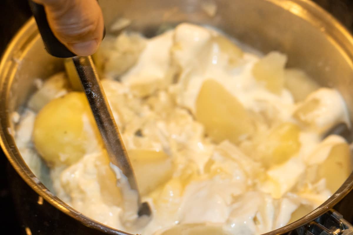 mashing the potatoes with a masher
