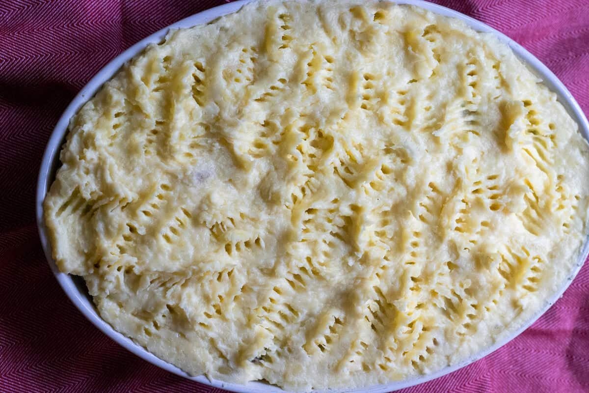 The meat filling is topped with mashed potatoes and is ready to bake