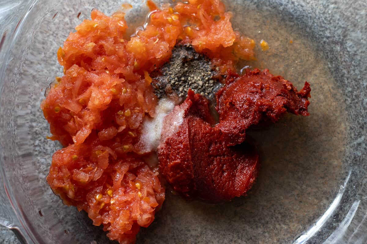 grated tomato, tomato paste and seasoning are placed in a bowl
