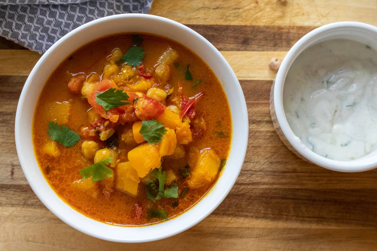 Butternut squash curry served with a bowl of raita