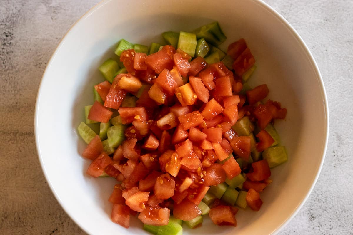 The diced tomatoes are added to the cucumbers