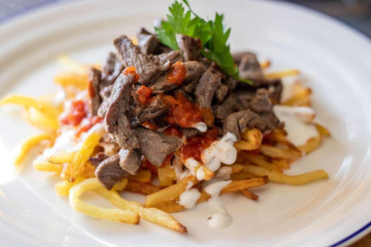 stir fried beef strips served with fried potatoes. yoghurt and tomato sauce