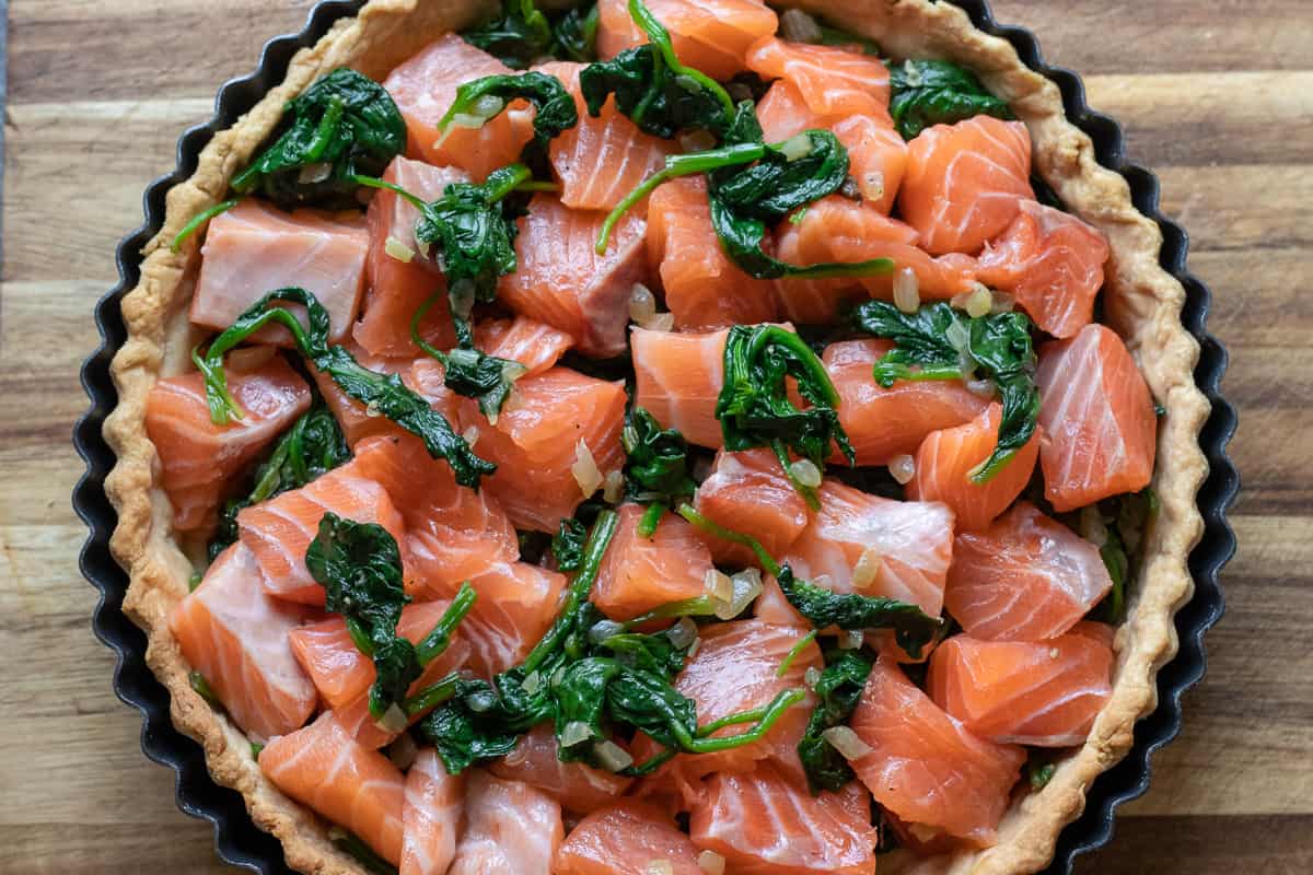 Salmon pieces and cooked spinach are in the crust