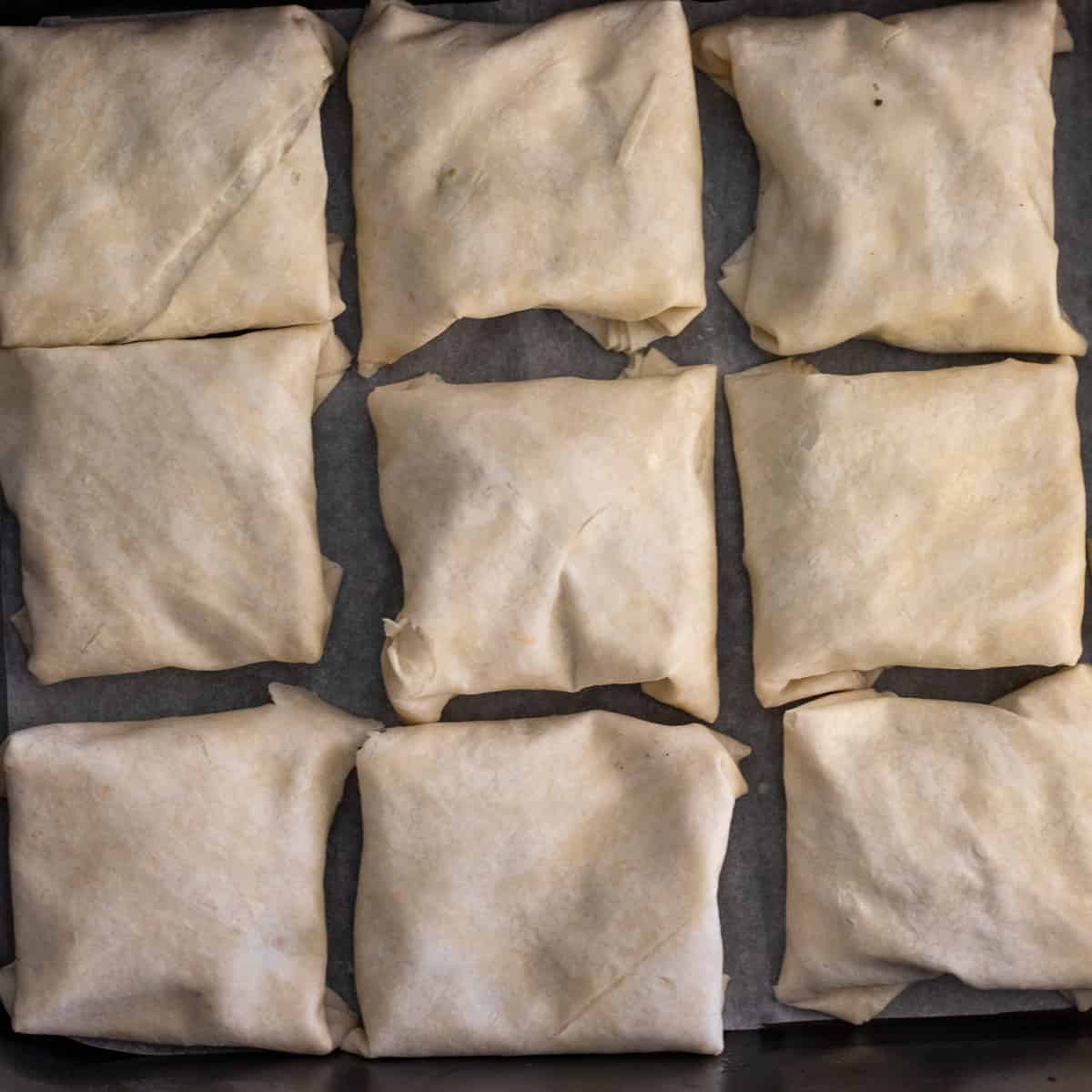 the borek parcels are placed on a baking paper lined tray
