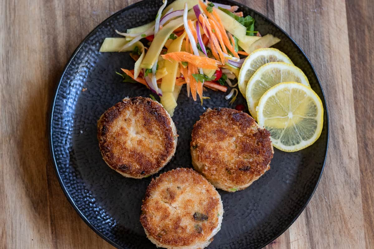3 pieces of crab cakes served with salad and lemon slices