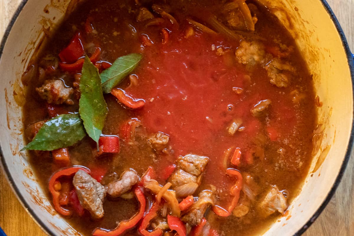 chopped tomatoes, stock and bay leaves are added to the pan