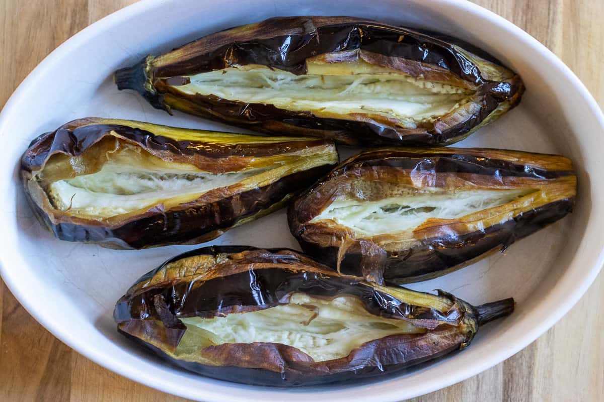 Aubergines are cut lengthwise and placed on a baking tray