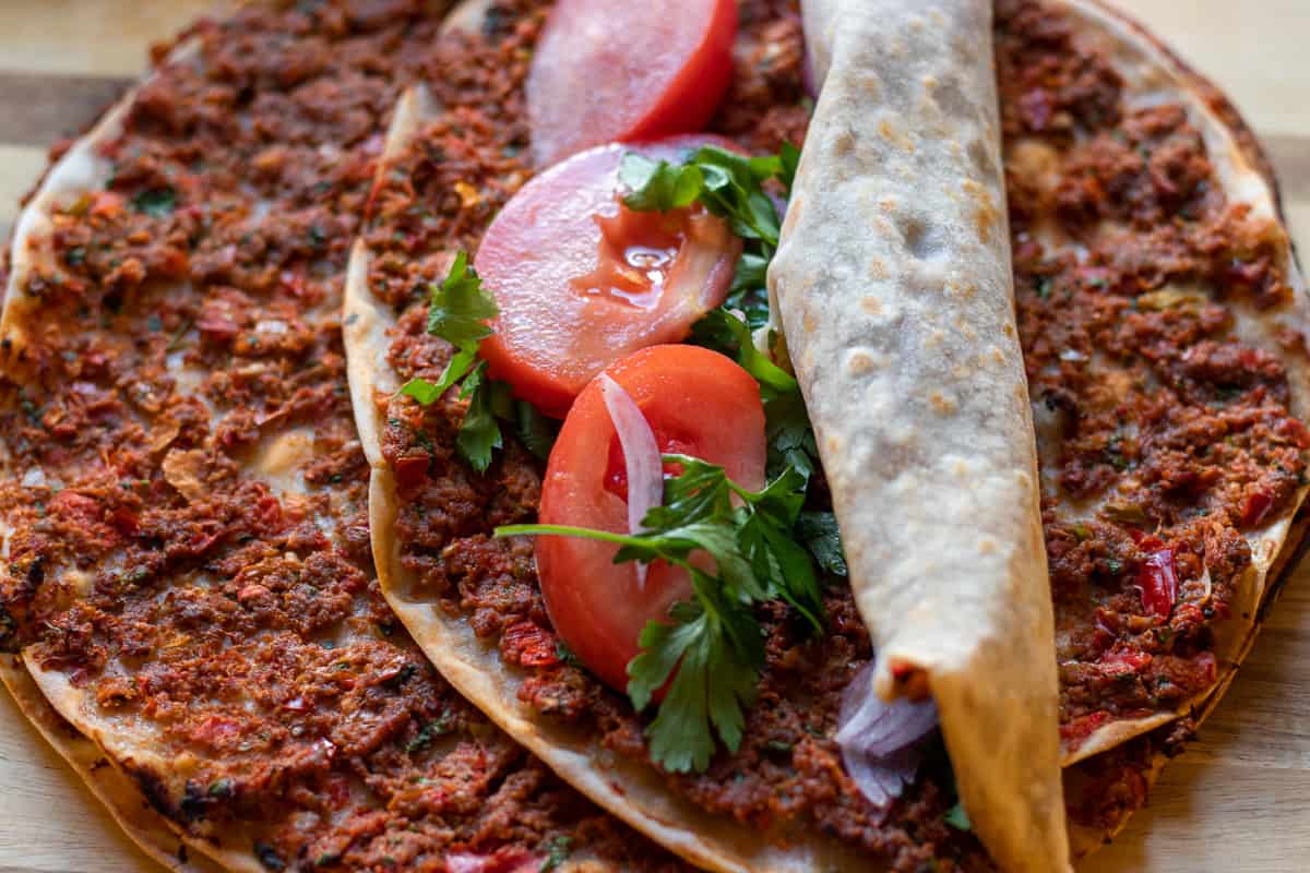 homemade Turkish lahmacun served with tomato slices and parsley