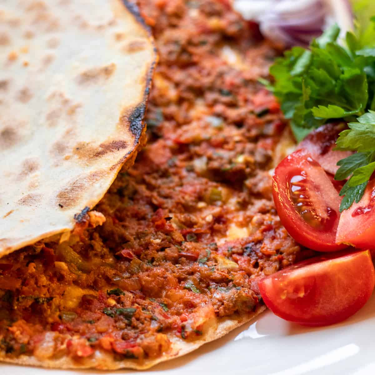 lahmacun served with fresh tomatoes and parsley
