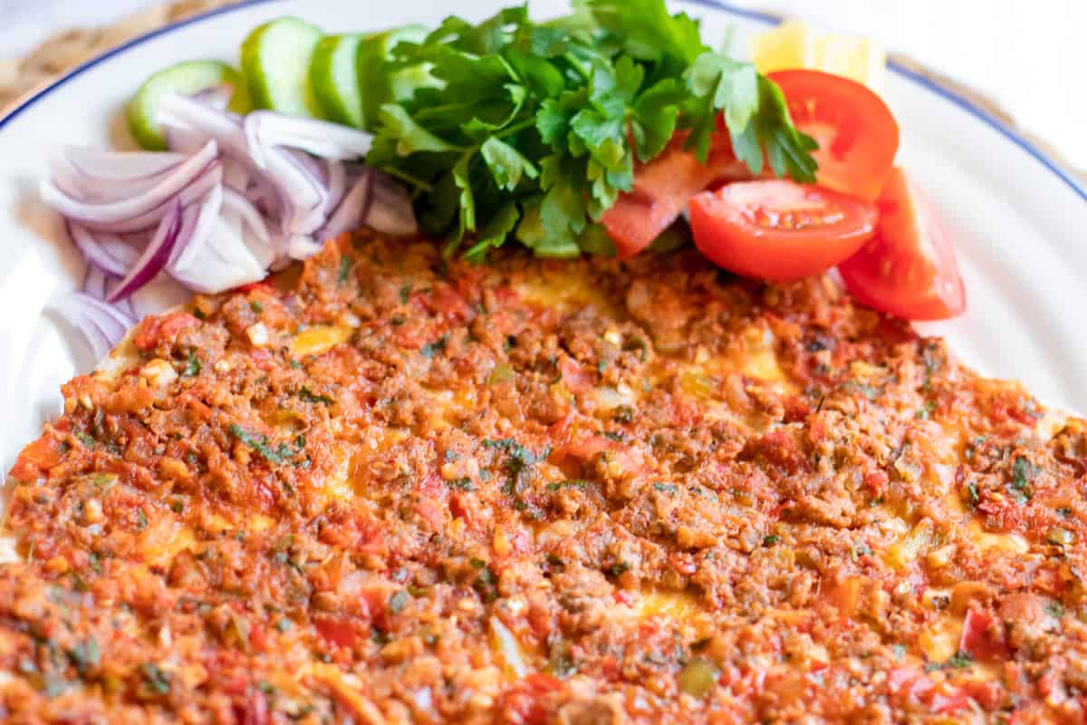 Turkish lahmacun is served with red onions, parsley, and tomatoes