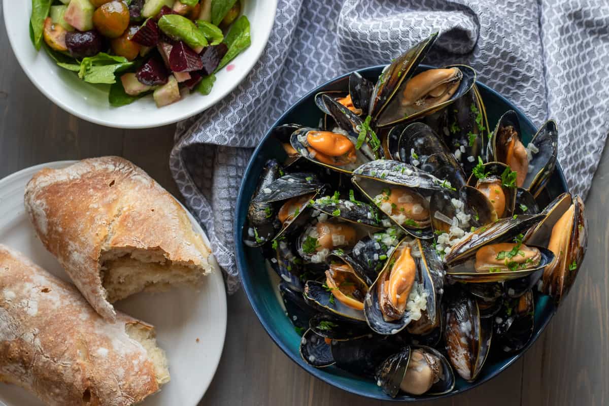 moules marinier is served with a bowl of salad and bread
