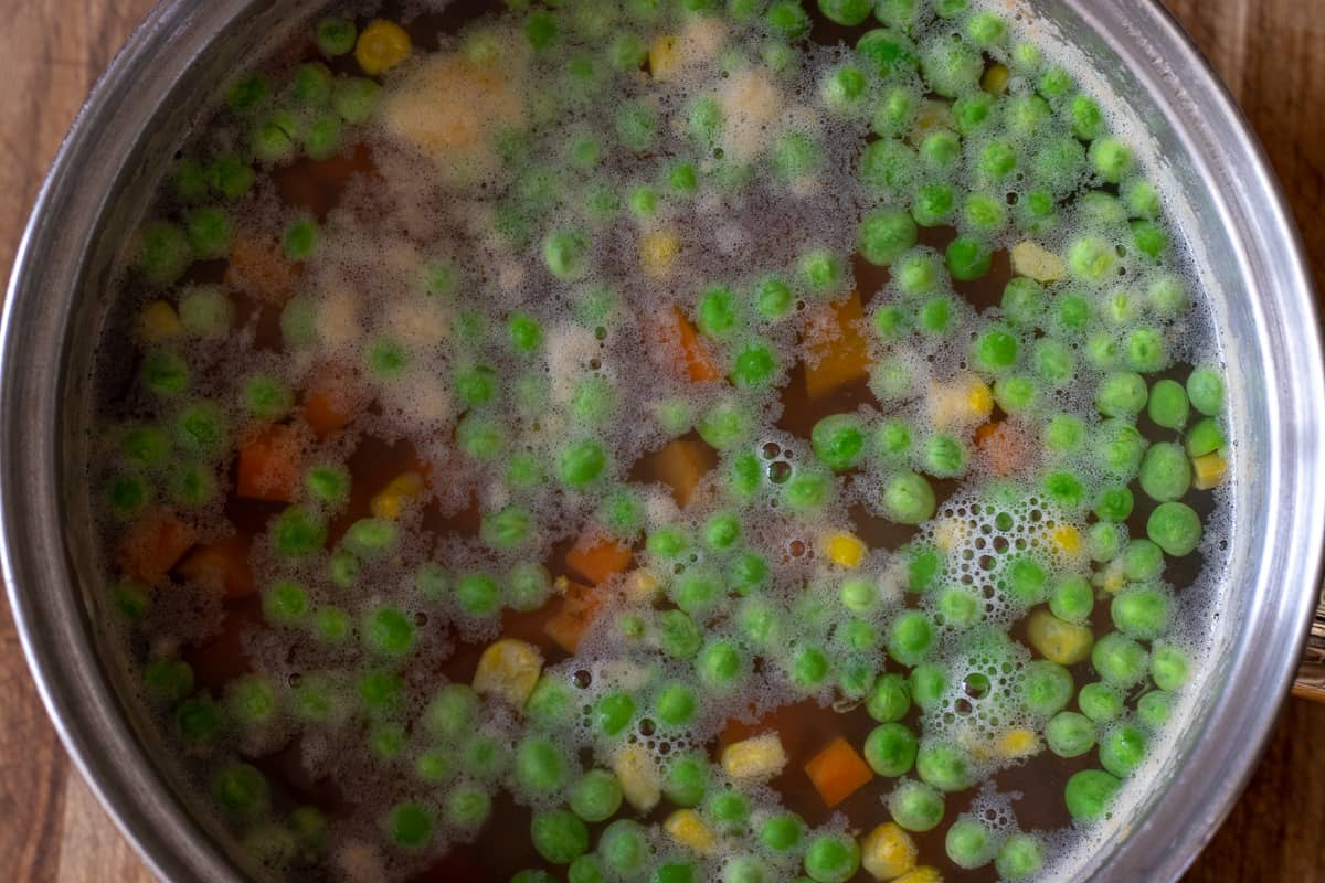frozen peas and sweetcorn are added to the pan with boiling water