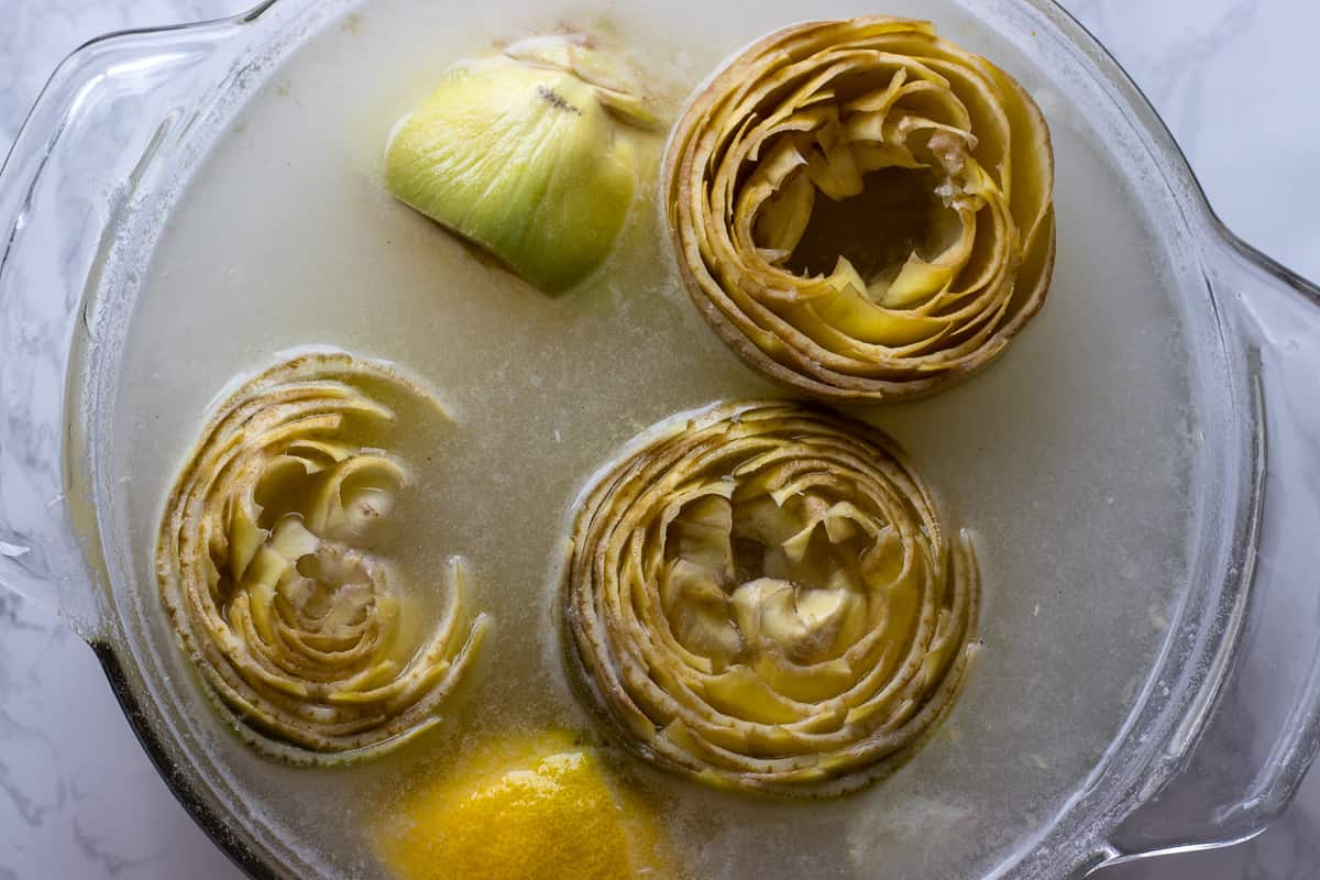 prepared artichokes are placed in a bowl with water and lemon juice