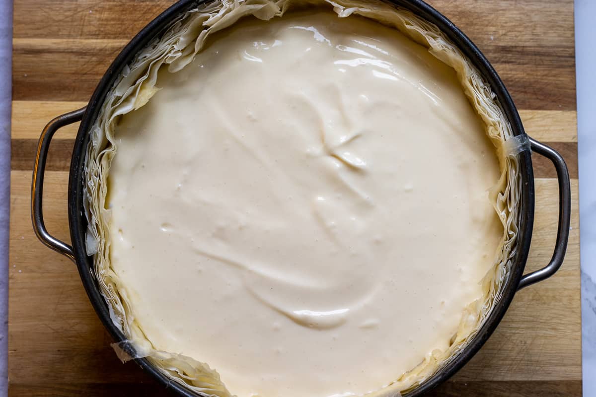 cream cheese filling is poured over the baklava crust