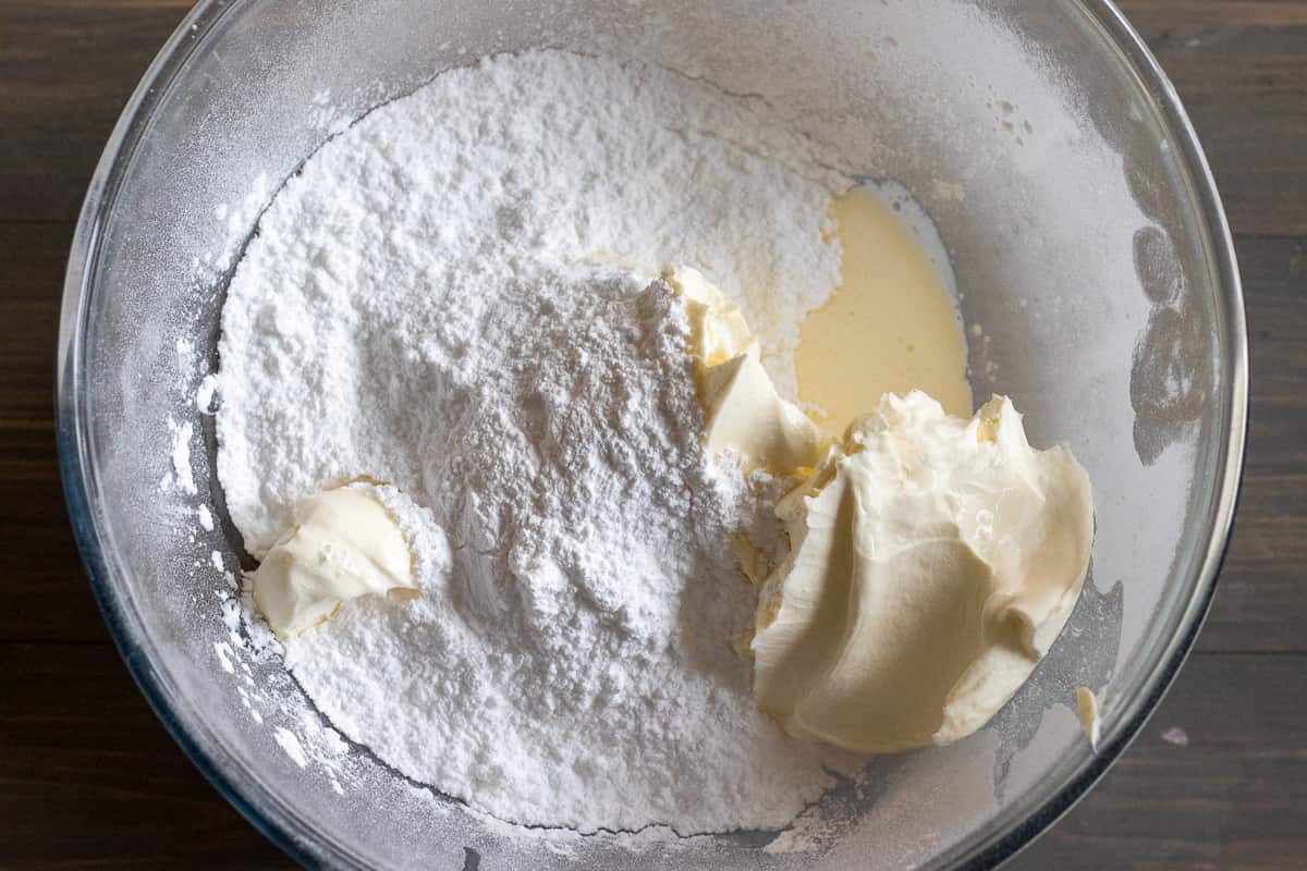 cream cheese, heavy cream and icing sugar are placed in a glass bowl