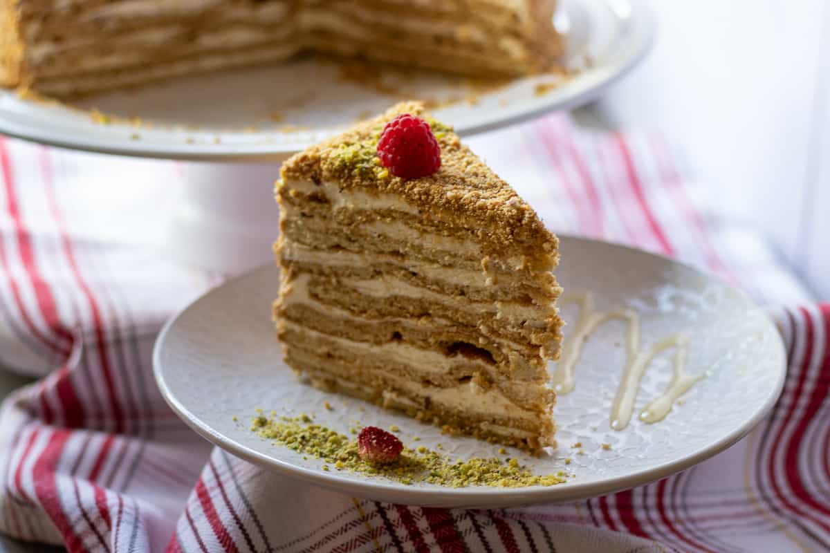 a slice of Russian honey cake served with pistachio and a drizzle of honey