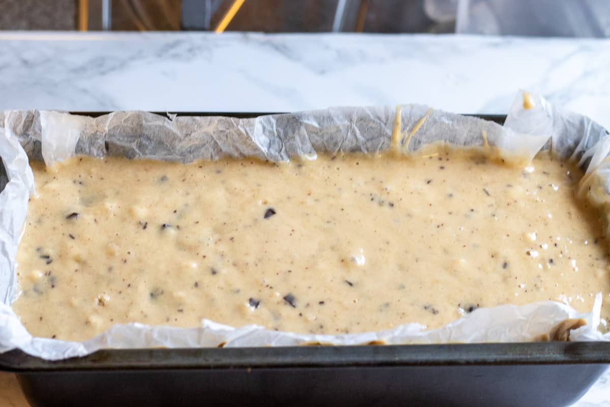banana bread mixture is placed in a loaf pan lined with silicon paper.
