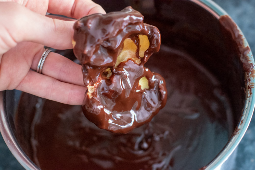 choux pastry is dipped in chocolate ganache
