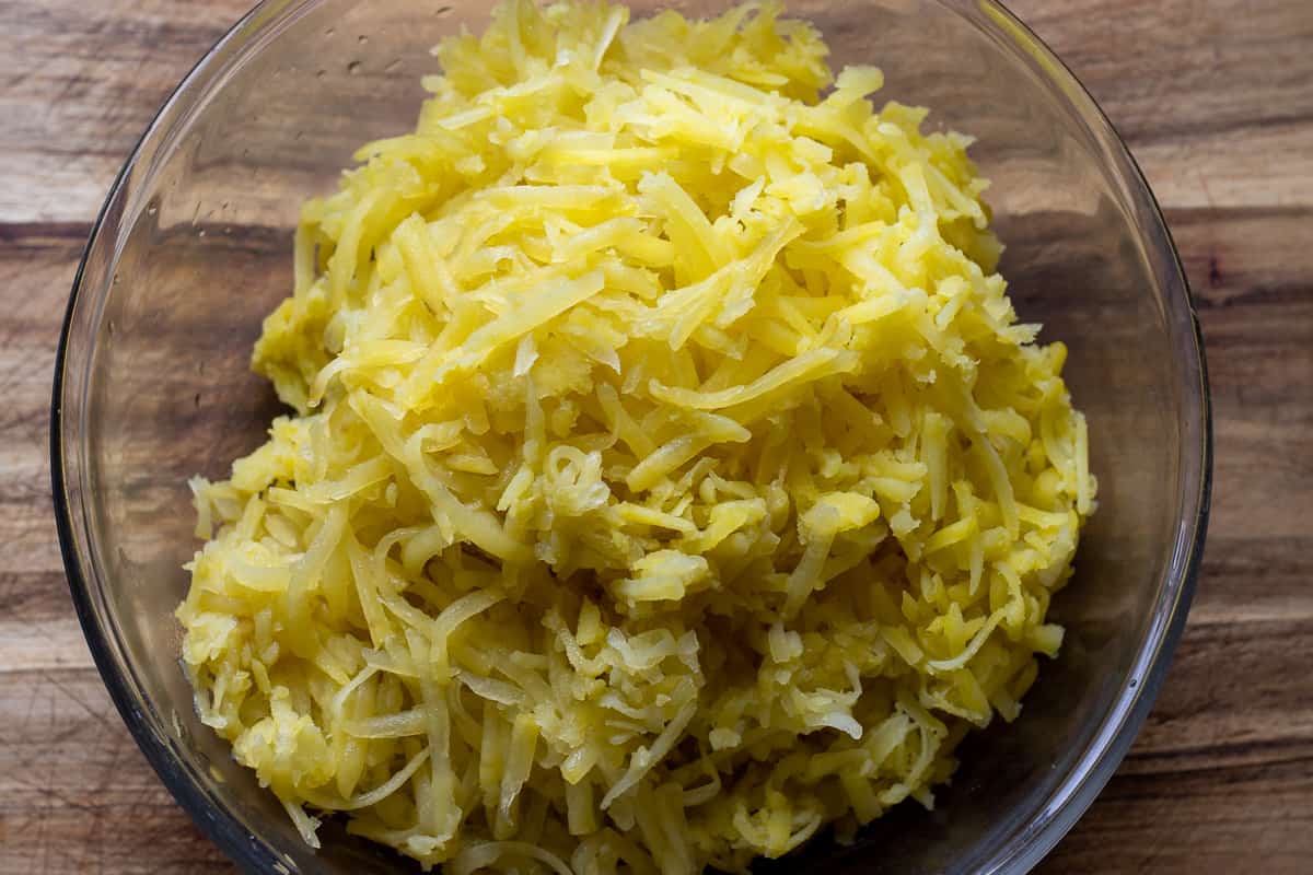 par boiled potatoes are grated in a large bowl