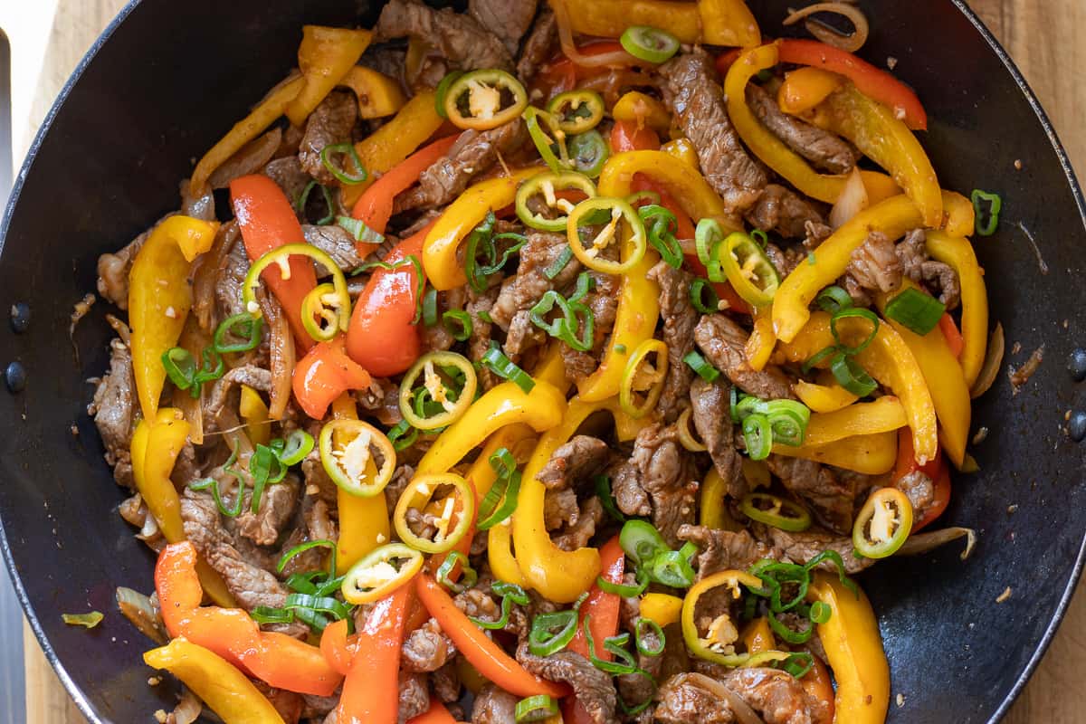 chilies and spring onion are added to the sautéed beef and vegetables 
