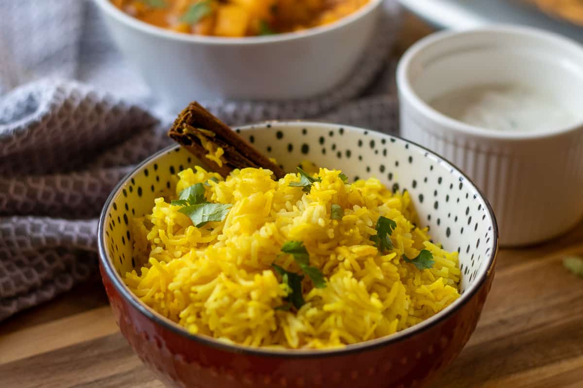 yellow rice served with curry and raita