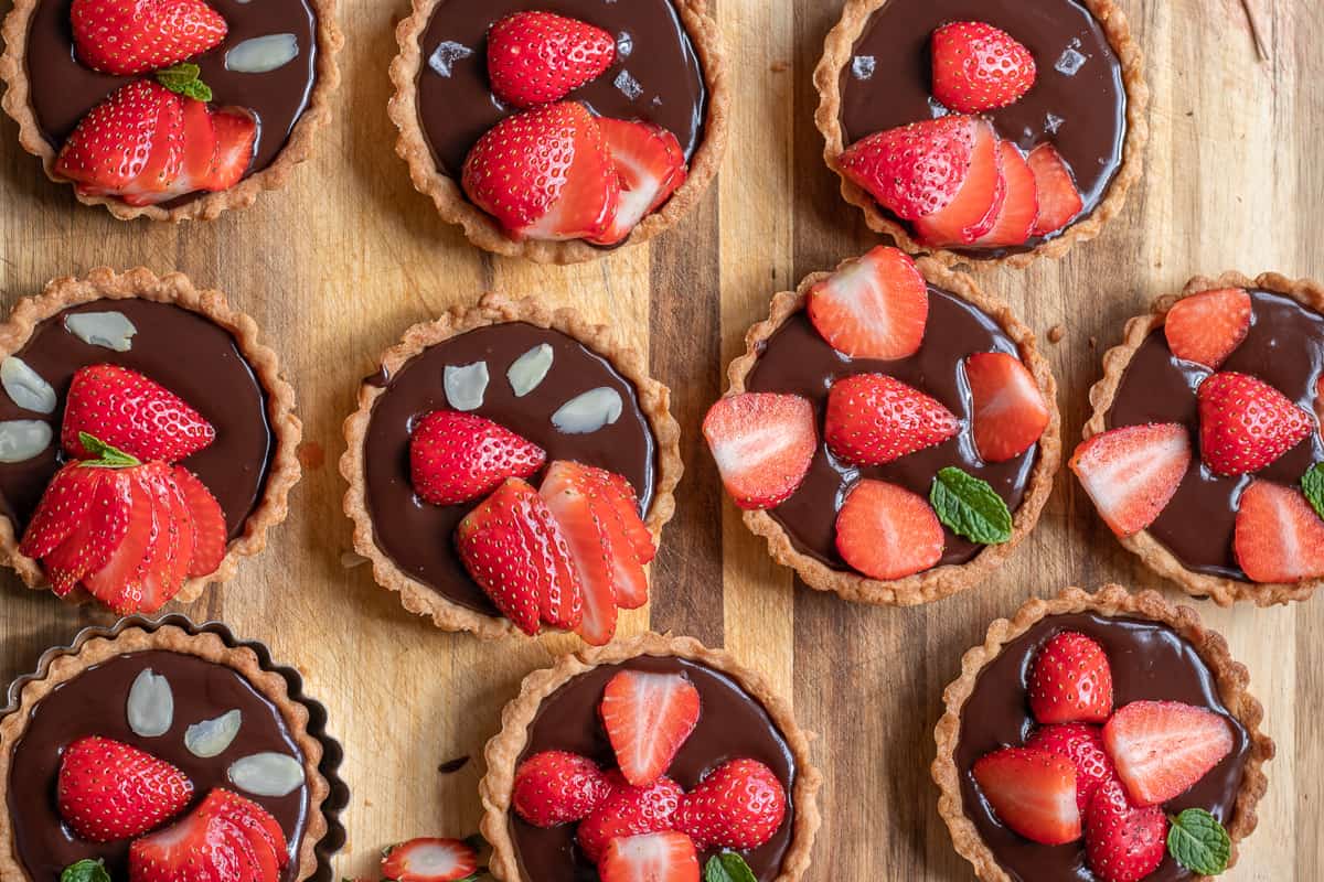 the tartlets are topped with fresh strawberries and almonds