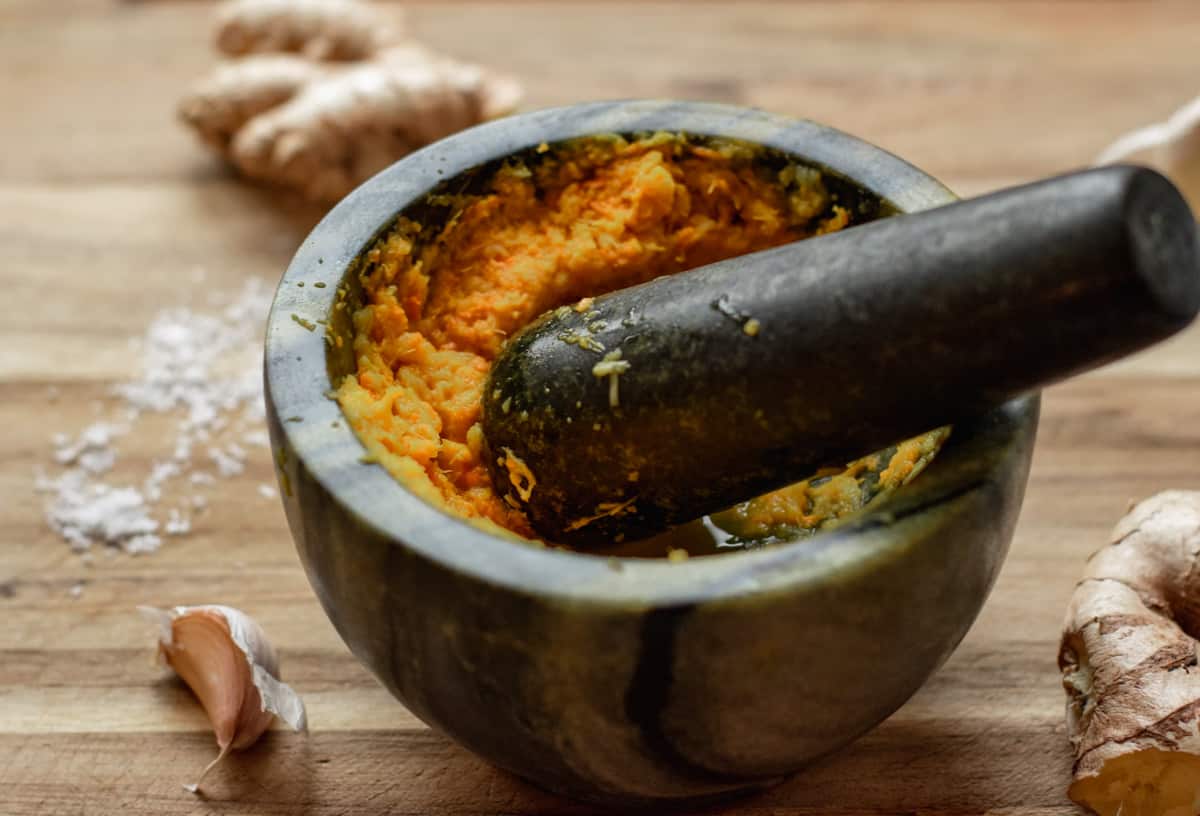 ginger, garlic and turmeric are pasted in a mortar using a pestle.