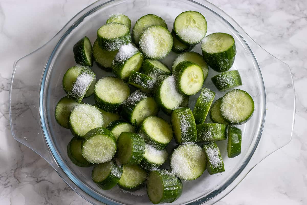 sliced cucumbers are covered with salt