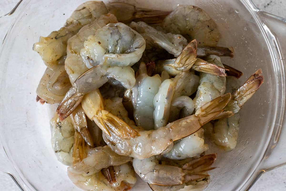 butterflied shrimps are mixed with the marinade in a bowl