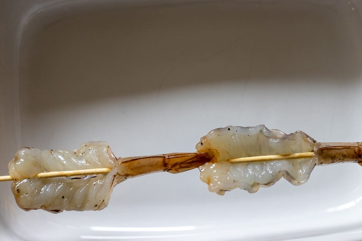 2 pieces of butterflied shrimp threaded on a bamboo skewer