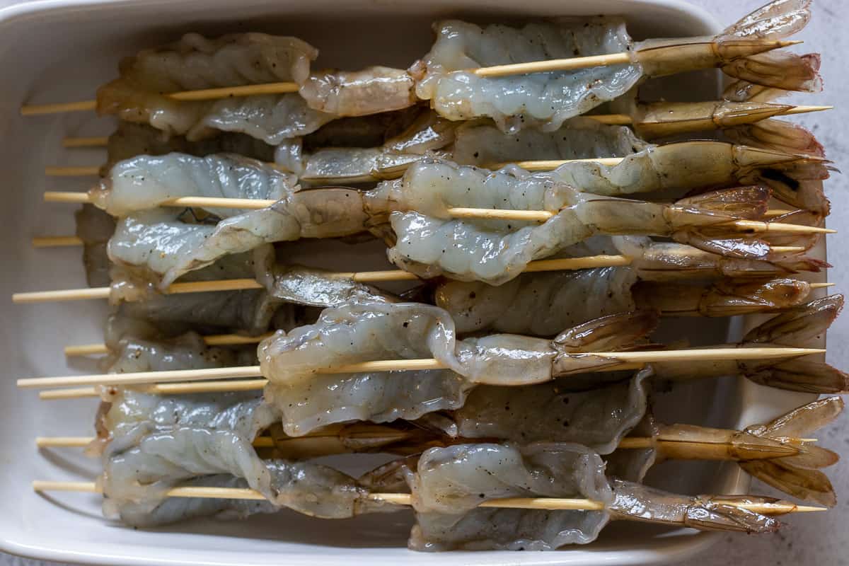 butterflied shrimps threaded on bamboo skewers are ready to cook on the barbecue