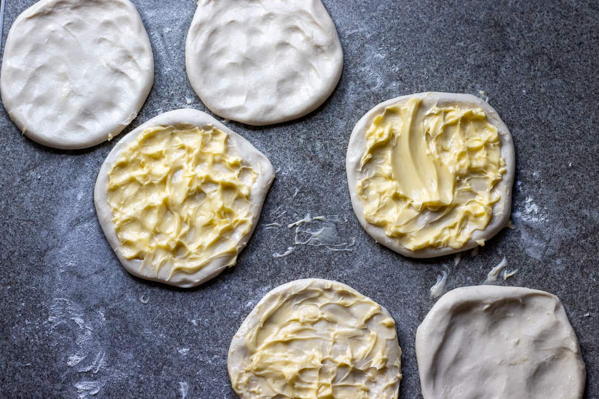 softened butter is spread on 3 dough circles