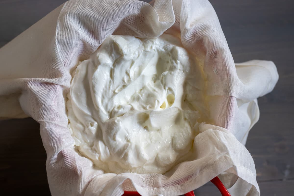 yogurt is placed in a cheesecloth over a sieve
