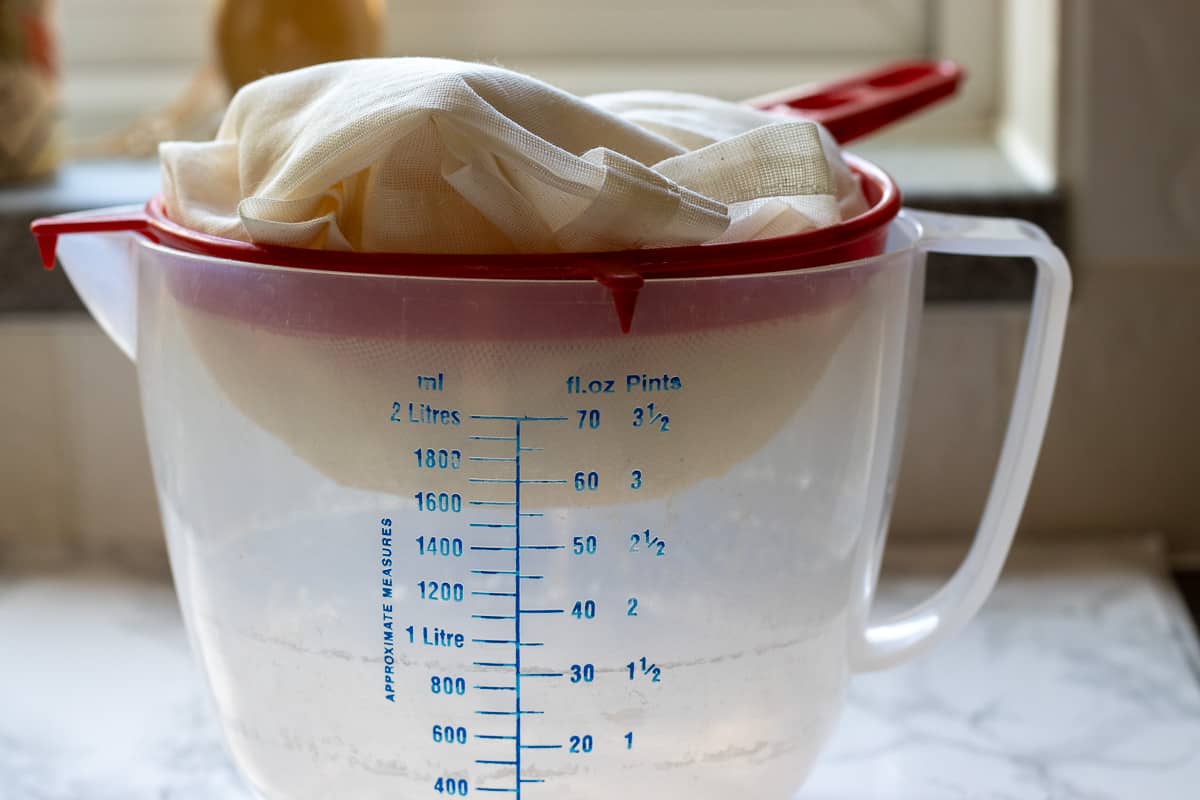 the sieve with cheesecloth is placed over a jug