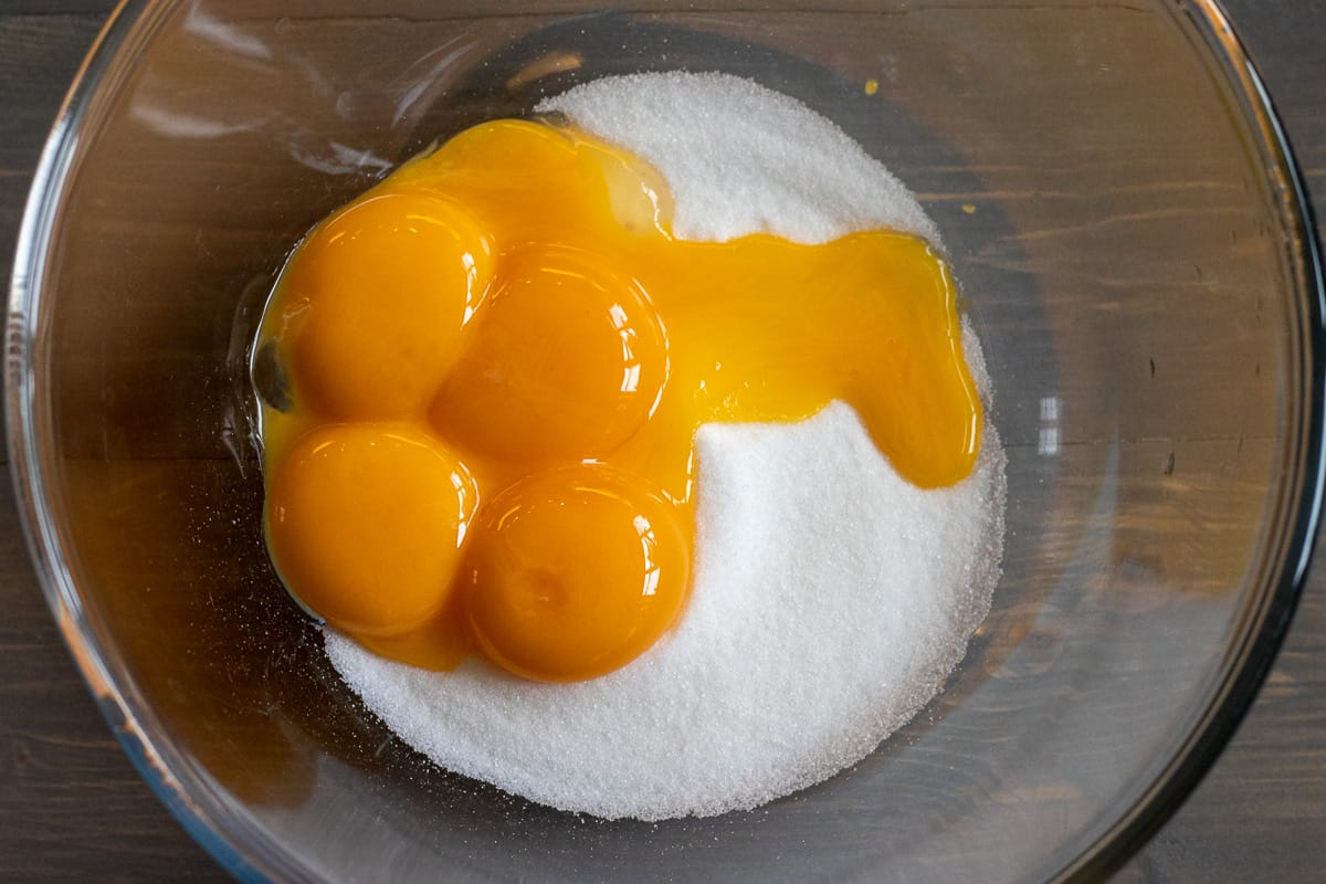 egg yolks and sugar are added to a glass bowl