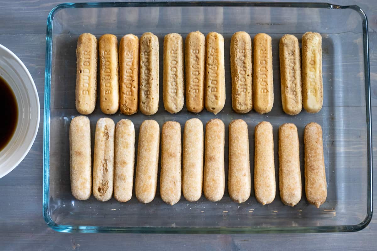 ladyfingers are dipped in coffee and arranged to the bottom of a baking dish