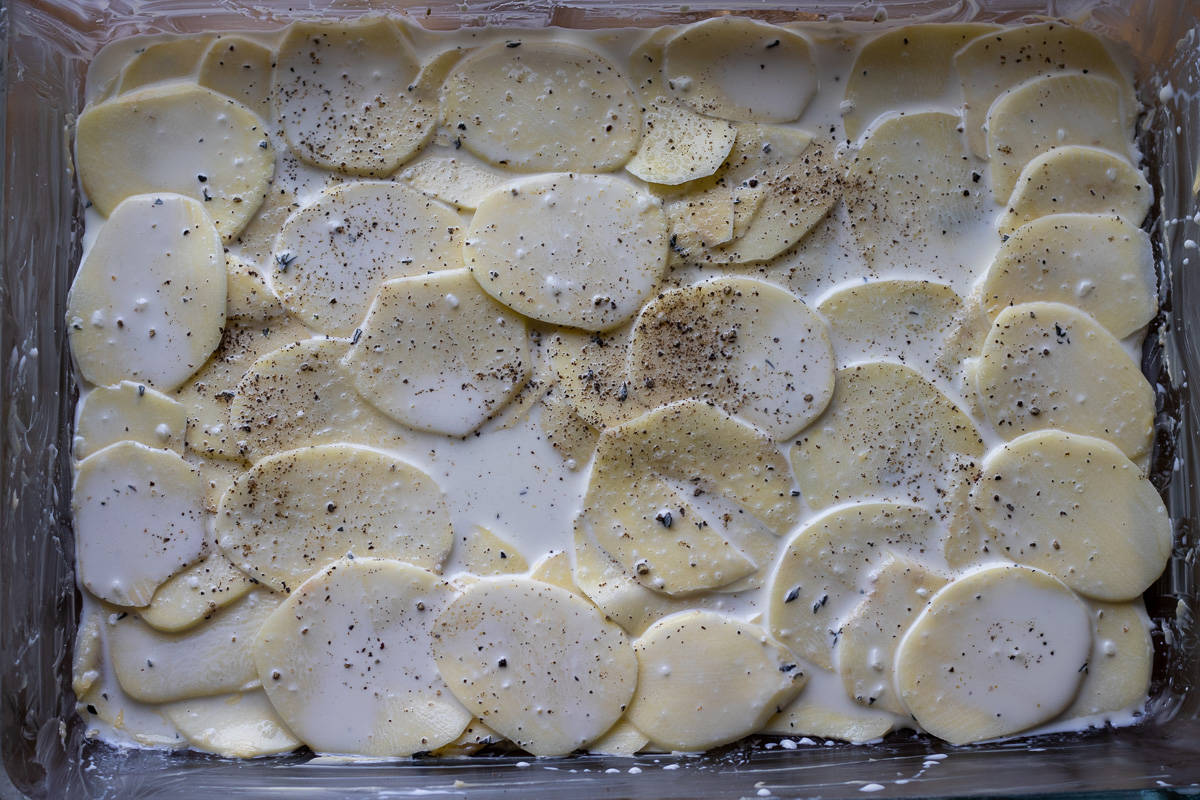 the first layer of potatoes layered on a bottom of the baking dish