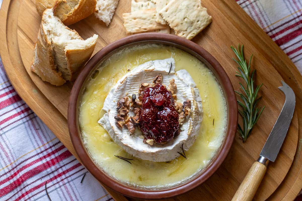 baked brie topped with walnuts and jam is served with baguettes and cheese biscuits