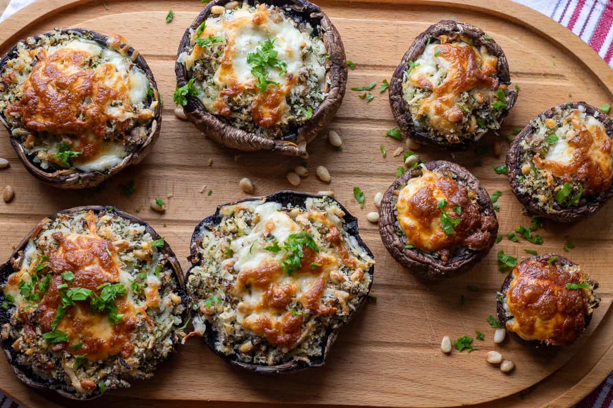 8 pieces of stuffed mushrooms on a wooden plate