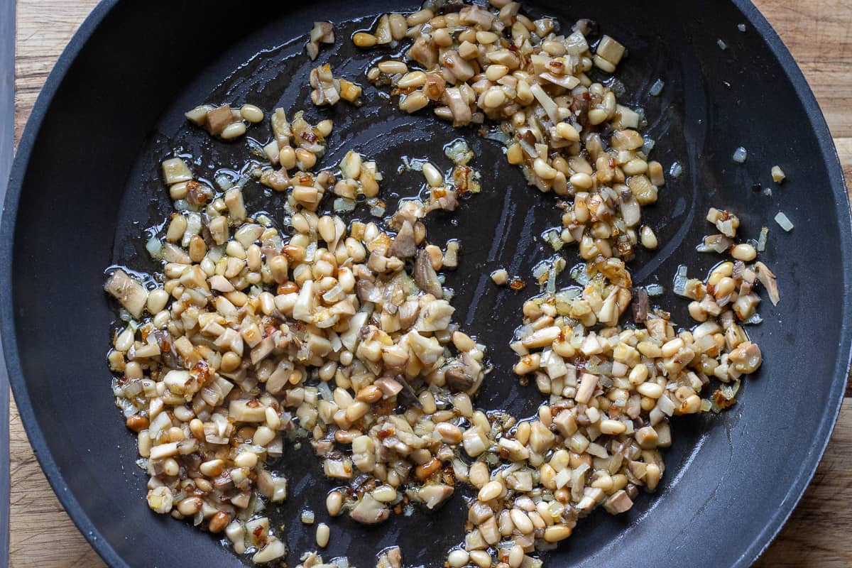 chopped mushroom stems are added to the pan for sautéing