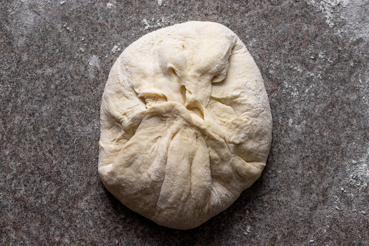 the sides of the dough is pulled up to seal and shape into a ball