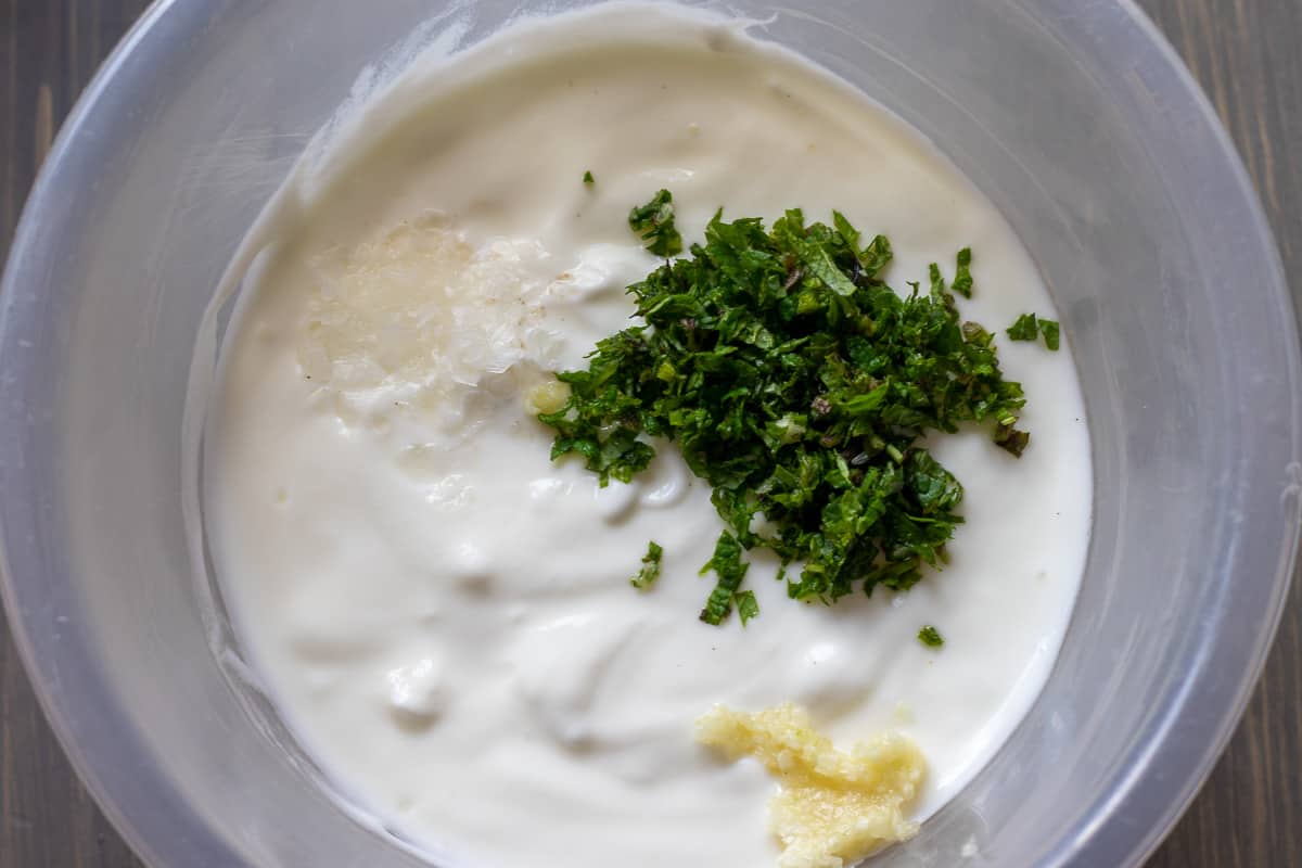yoghurt is mixed with garlic and chopped herbs