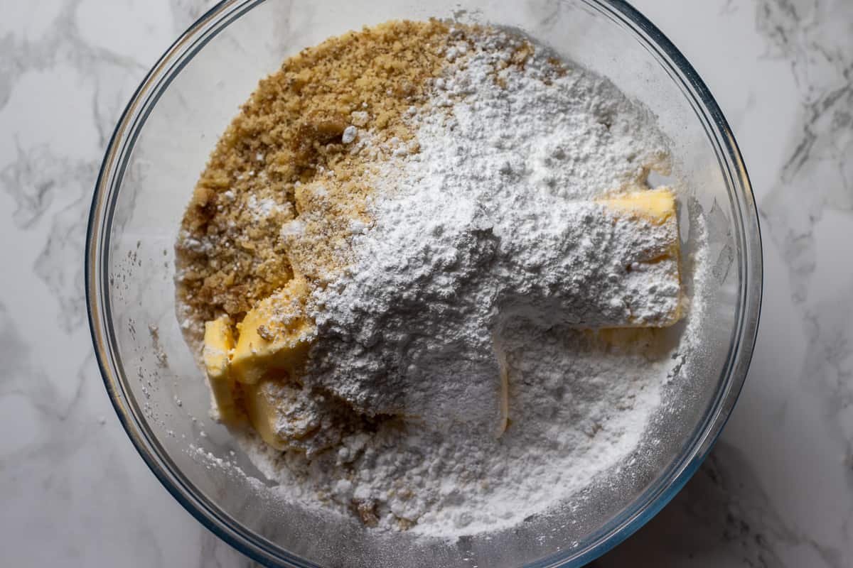 softened butter, walnuts, icing sugar, and flour are placed in a mixing bowl