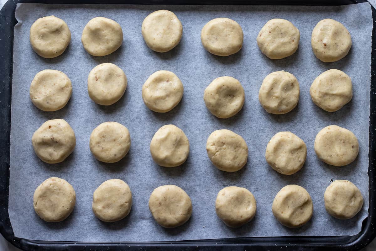 24 pieces of walnut cookie dough are placed on a baking sheet