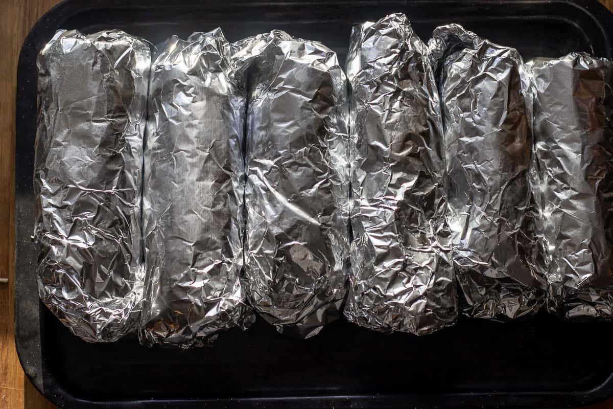 6 pieces of burritos wrapped in tin foil and placed in a baking sheet